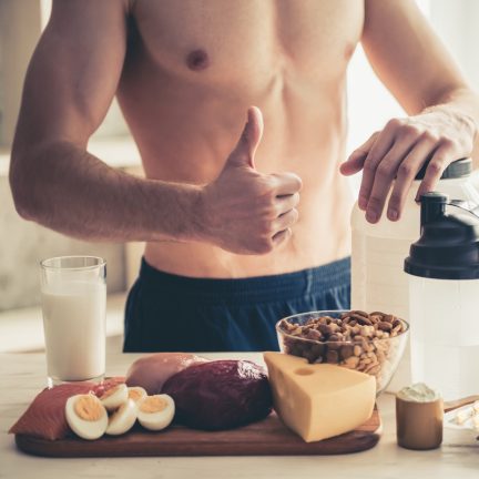 Cropped image of handsome young sportsman showing Ok sign while preparing sport nutrition in kitchen at home
